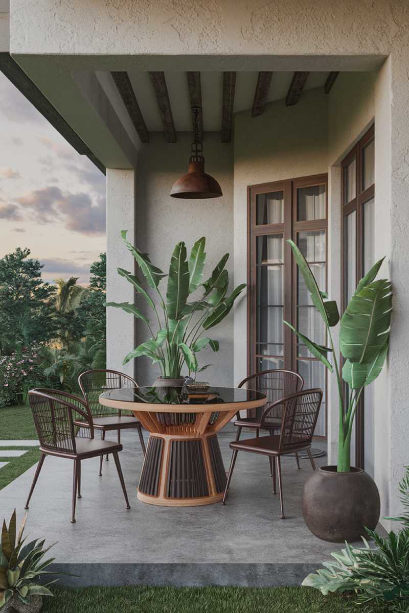 A modern patio design with a stylish and highly detailed decor. There's a wooden table with a glass top and four chairs, made of metal with a dark brown finish. The floor is made of concrete. There's a large potted plant with green leaves near the entrance. The wall has a textured finish and is painted in a light grey color. There's a hanging lamp made of metal with a dark brown finish. The patio is surrounded by a lush green landscape. The sky has a few clouds.